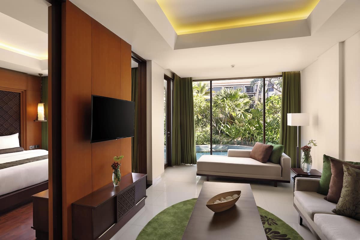 Ein Hotelzimmer mit Bett, einer Couch, einem Fernseher und Blick auf Pool und Grünflächen.