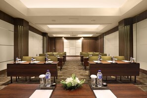 A conference room with a long table, multiple chairs, water bottles, and a floral centerpiece. - Golden Tulip Jineng Resort Bali (Kuta)
