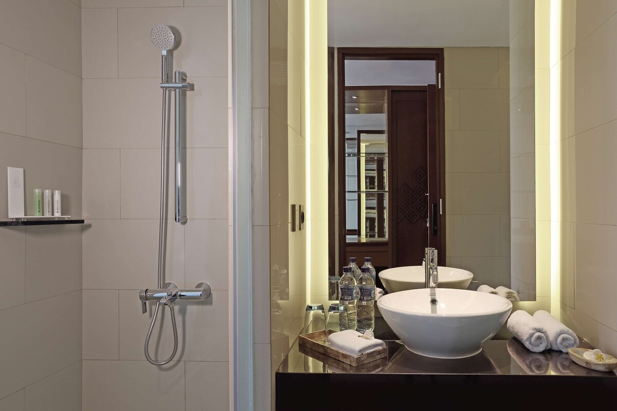 Une salle de bain moderne avec un grand miroir, un lavabo et une douche.