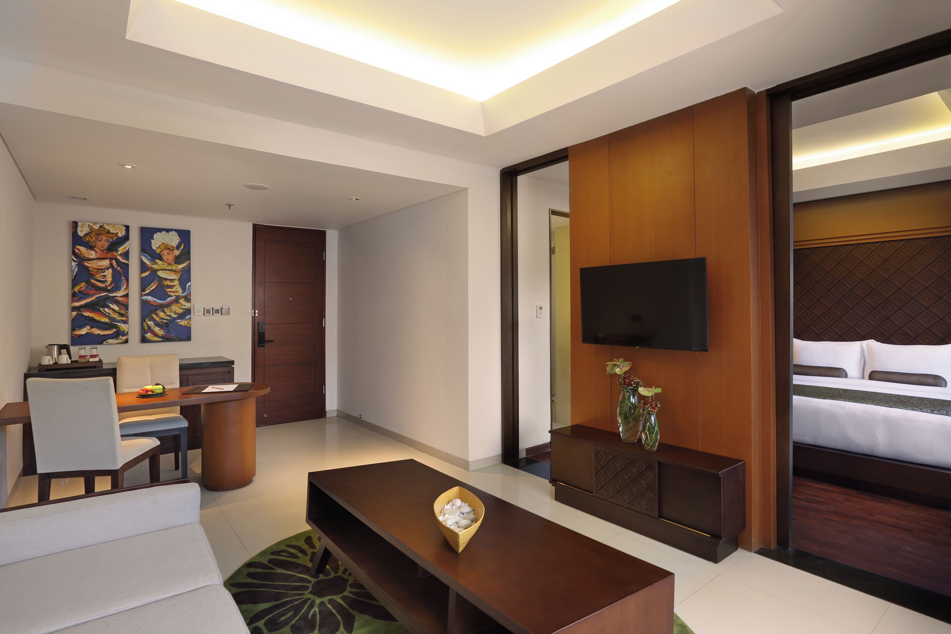 A hotel room with a bed, a TV, a desk, and a coffee table.