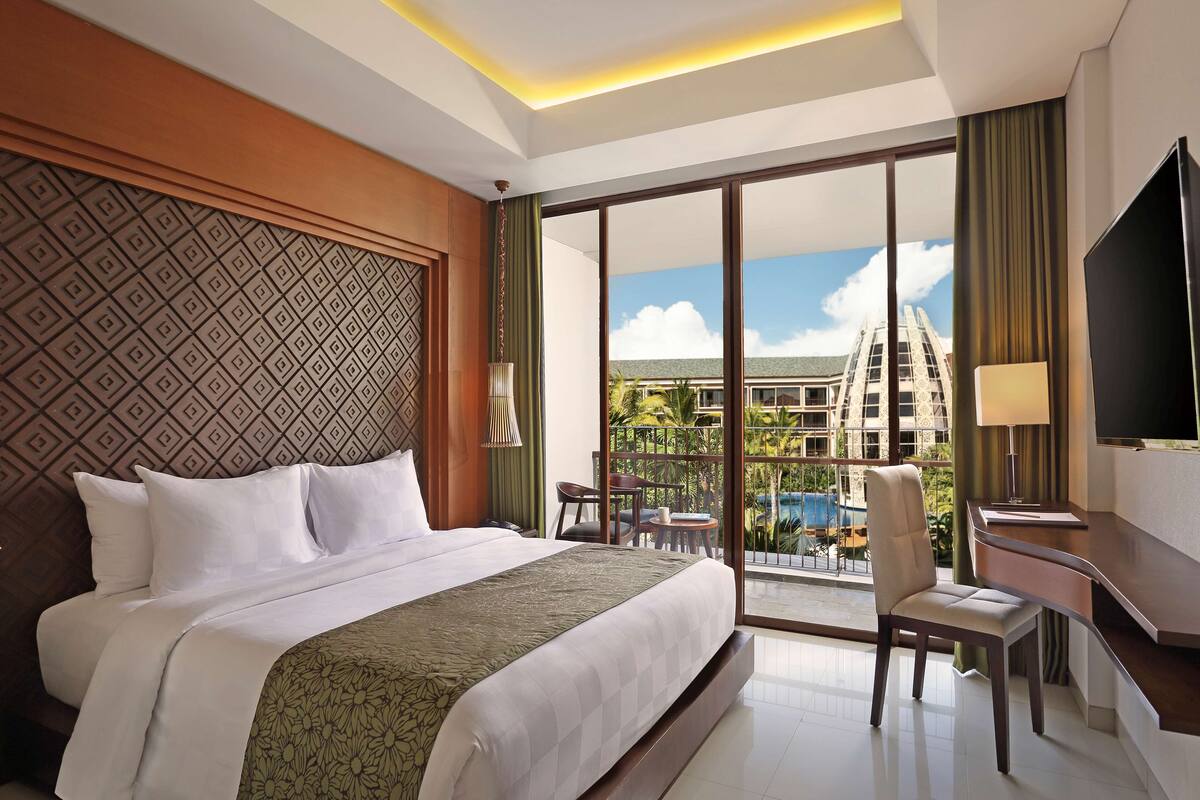 Ein Hotelzimmer mit einem großen Bett, einem Schreibtisch, einem Stuhl und einem Fernseher.