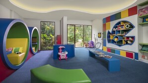 Ein Kinderspielbereich mit bunten Sitzgelegenheiten, einer Spielküche und einem Bücherregal.
