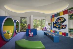 A children's play area with colorful seating, a play kitchen, and a bookshelf. - Golden Tulip Jineng Resort Bali (Kuta)