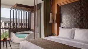 Ein Hotelzimmer mit einem großen Bett, einer Badewanne und einem Balkon mit Blick auf Gebäude.