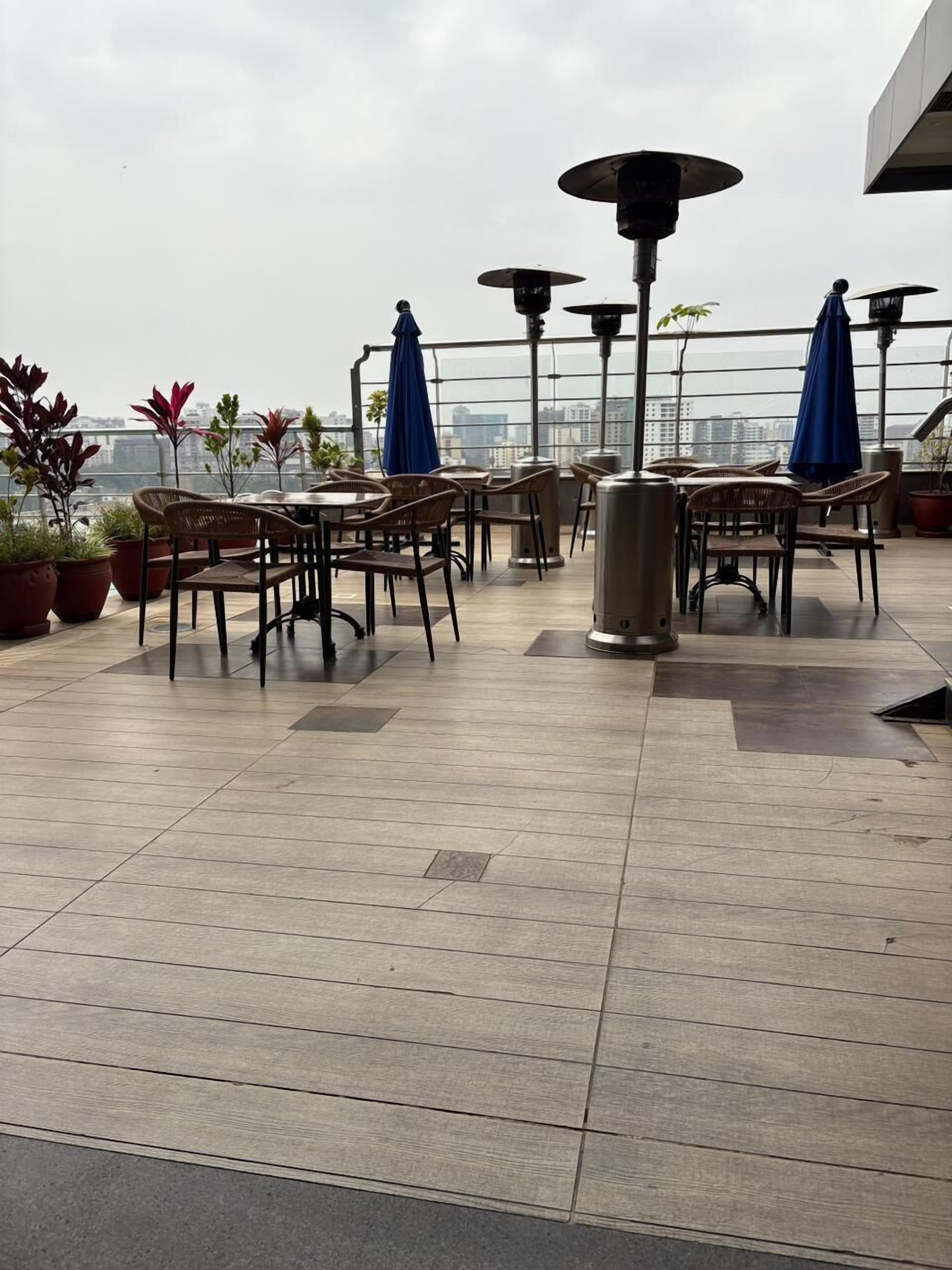 Una terraza en la azotea con mobiliario exterior, plantas en macetas y vistas a la ciudad.