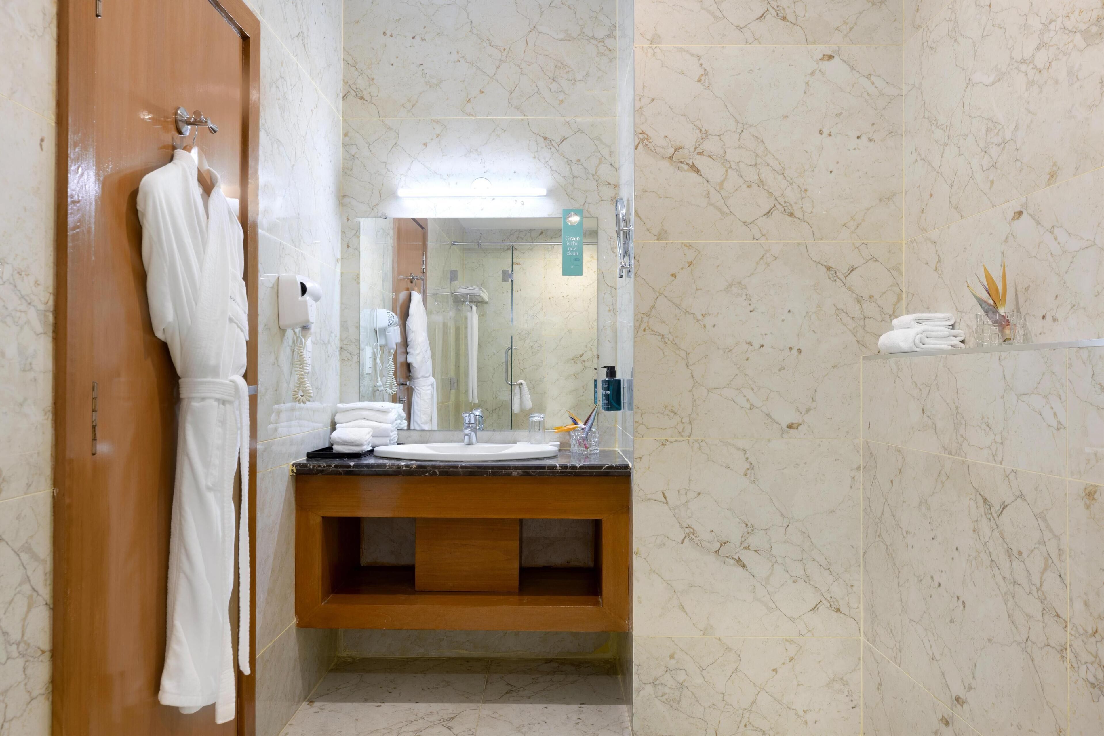 A bathroom with a wooden vanity, a mirror, a sink, and a robe hanging on the wall.