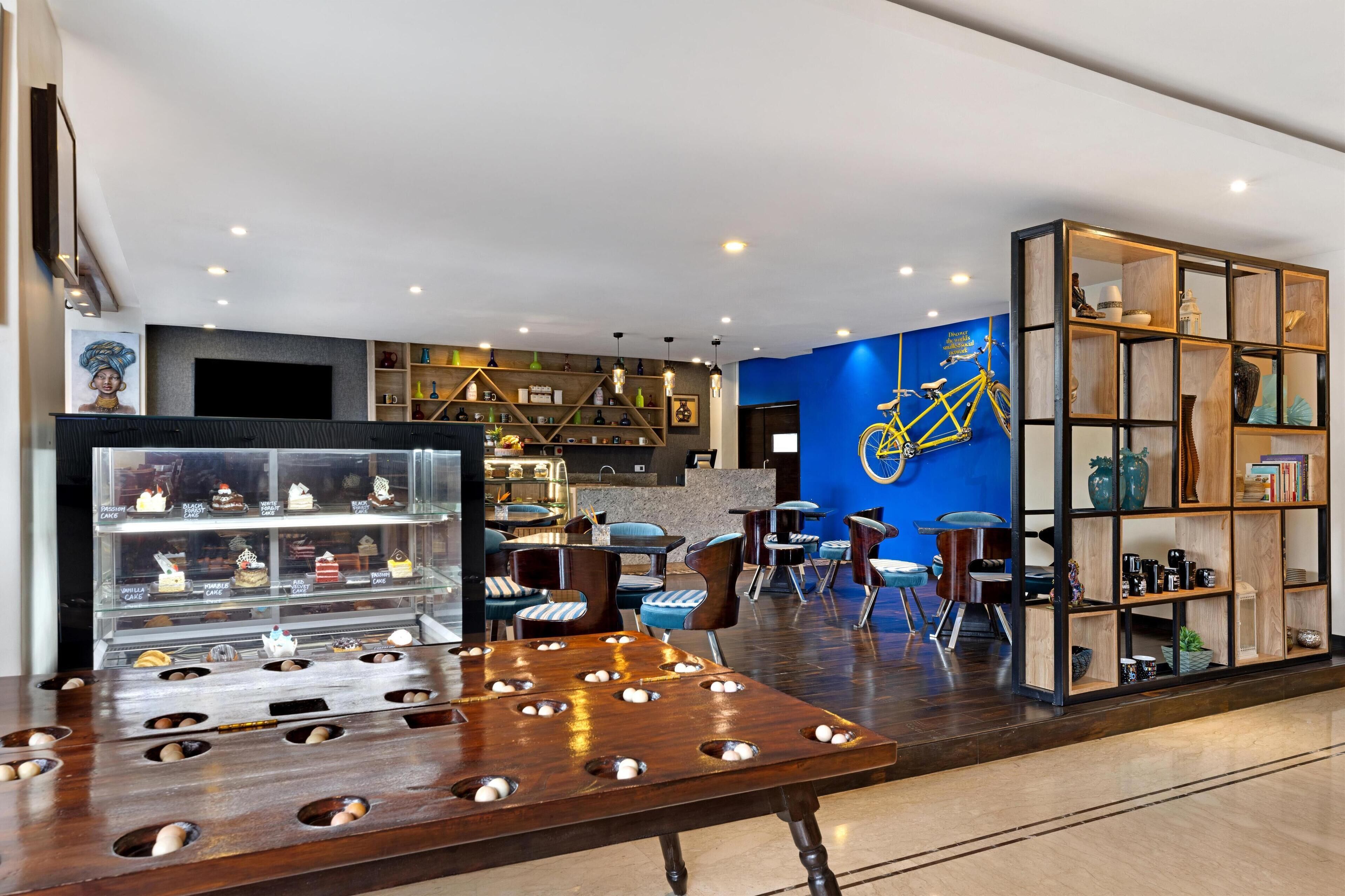 A modern interior with a seating area, a display case with desserts, and a blue wall with a bicycle illustration.