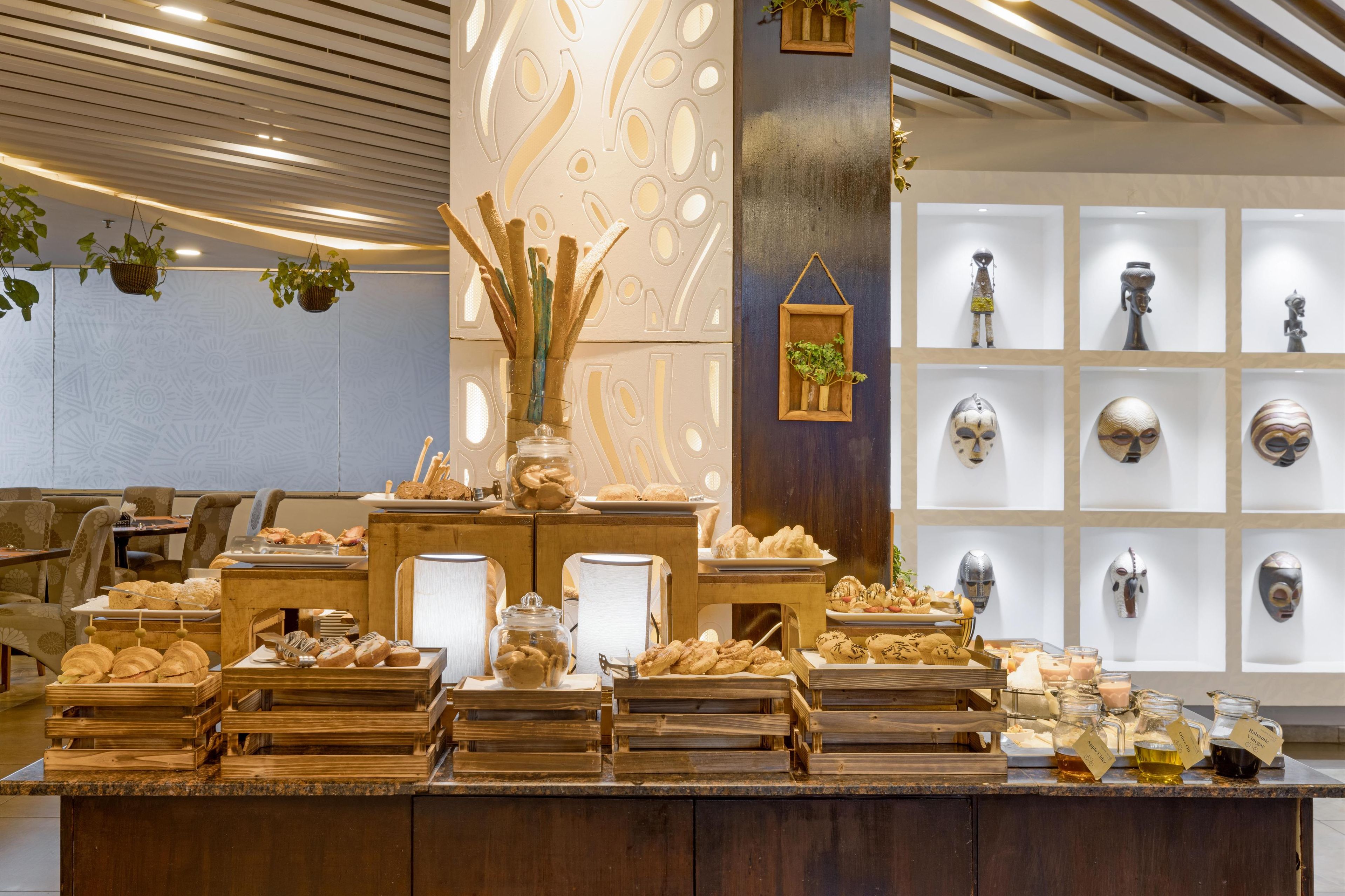 A buffet with various food items and a display of decorative masks.