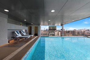 Una piscina al aire libre, sombrillas, tumbonas