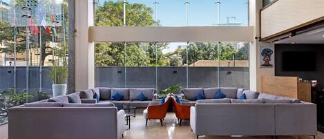 Un vestíbulo espacioso con un sofá seccional gris grande, sillas naranjas y una mesa de centro.