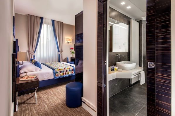 Une chambre d’hôtel moderne équipée d’un lit, d’une table de chevet, d’une lampe et d’une grande fenêtre avec des rideaux.