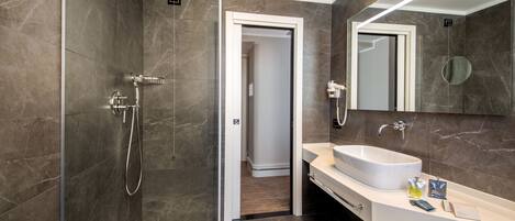 Un baño moderno con ducha de vidrio, un lavamanos grande y un espejo.