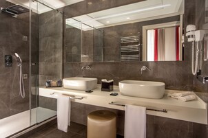 A modern bathroom with two sinks, a glass shower enclosure, and a large mirror.