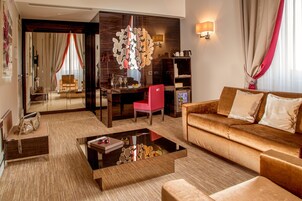 A modern living room with a sofa, coffee table, and a red chair. There is a dining area with a table and chairs, and a large mirror on the wall.