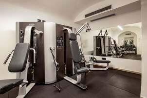 Et fitnesscenter med løbebånd, vægtbænke og håndvægte.