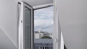 A bedroom with a bed, a window, and a view of buildings. - Paradise Hotel (Paris)