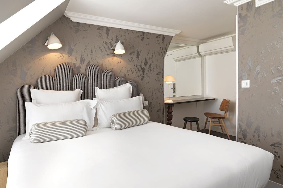A bedroom with a large bed, a desk, a chair, and a mirror.