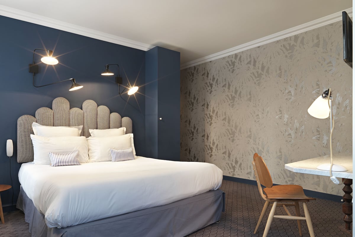 A bedroom with a bed, two bedside lamps, a chair, and a desk.