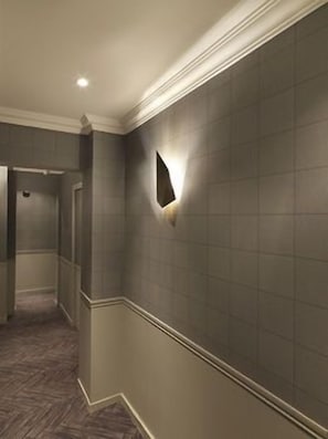 A hallway with a textured wall, a light fixture, and a carpeted floor.