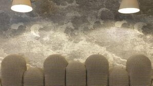 A room with a patterned wall, two wall-mounted lamps, and a row of patterned chairs. - Paradise Hotel (Paris)