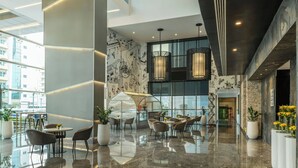 A modern lobby with a glass canopy, seating areas, and a view of the cityscape. - The First Collection Marina, Dubai, a Tribute Portfolio Hotel (Dubai)