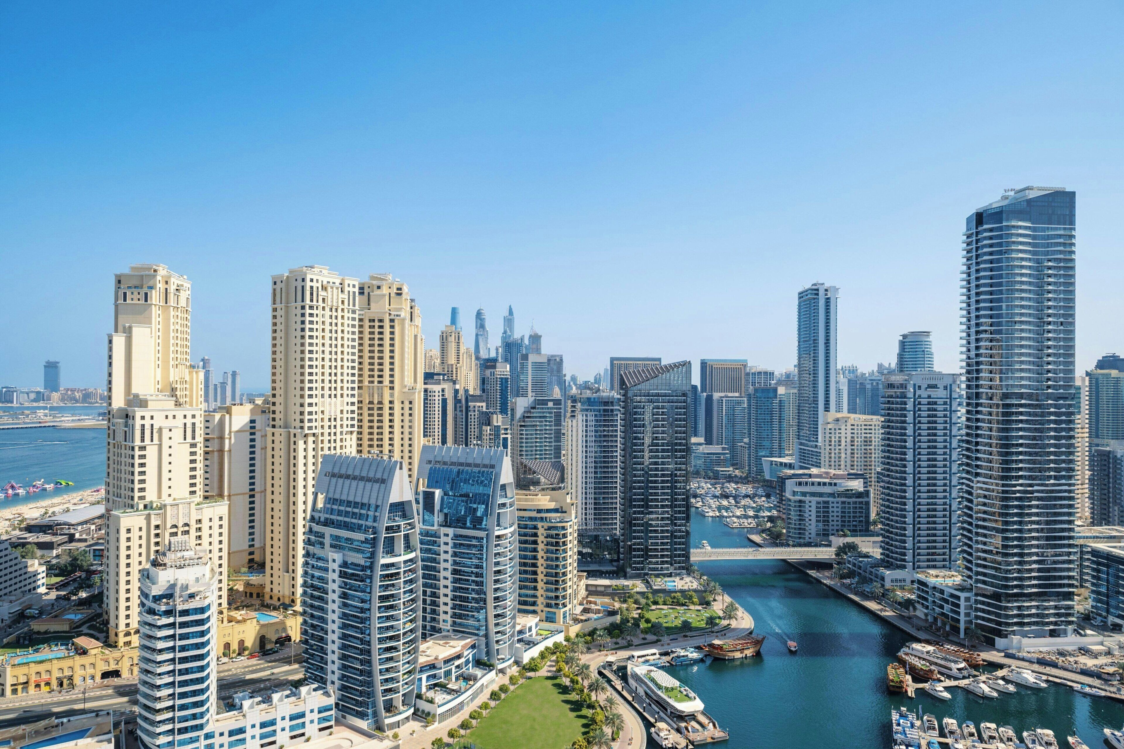 A high-rise urban skyline with a marina and waterway.