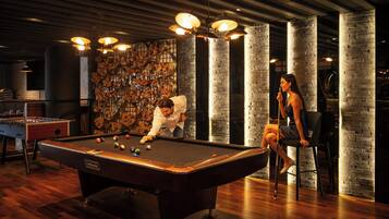 A billiards table, a foosball table, and a wall with numerous photos.