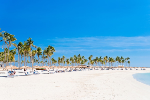 Een privéstrand, wit zand, ligstoelen aan het strand, parasols