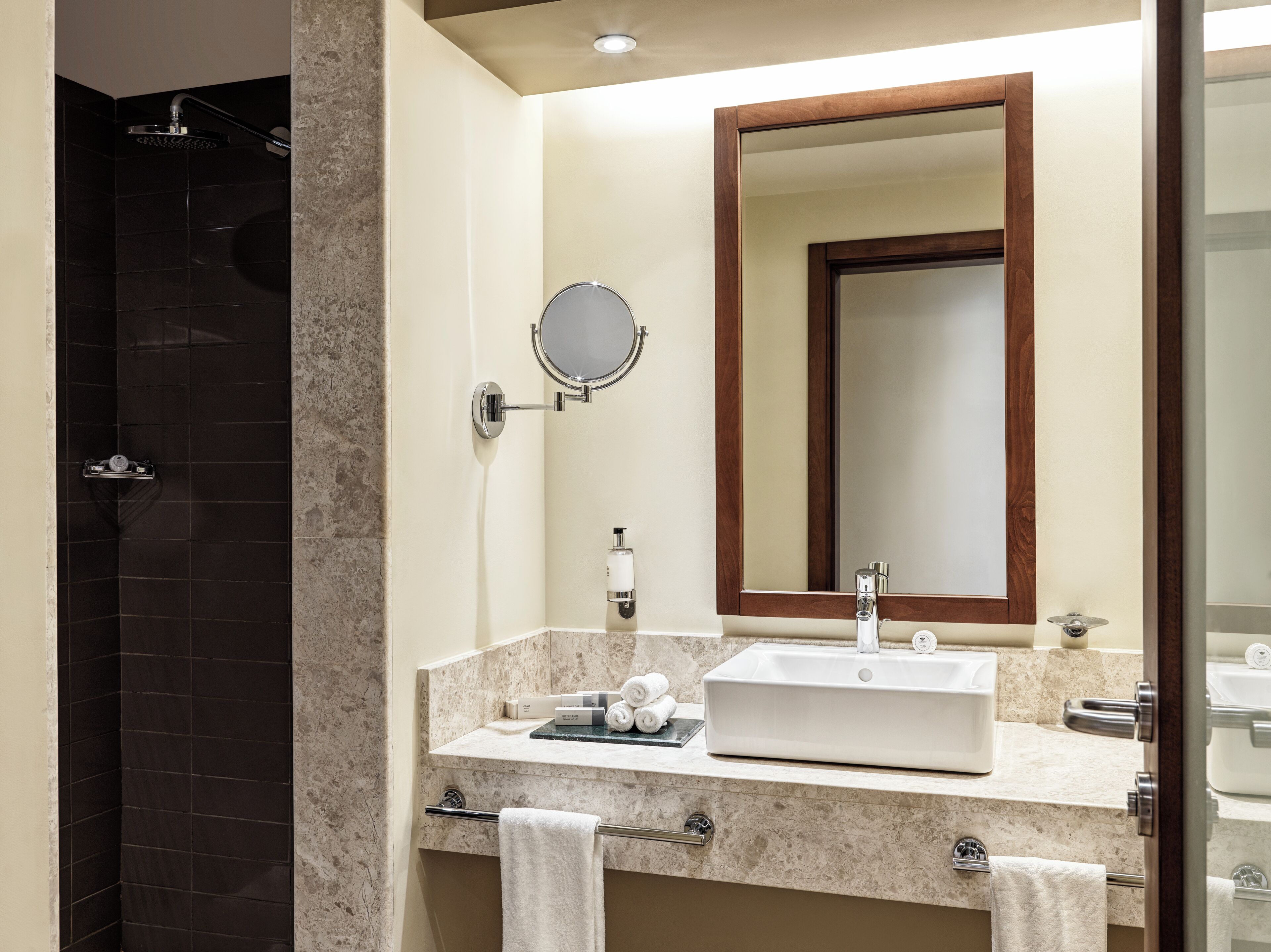 A modern bathroom with a shower, a sink with a mirror, and a towel rack.