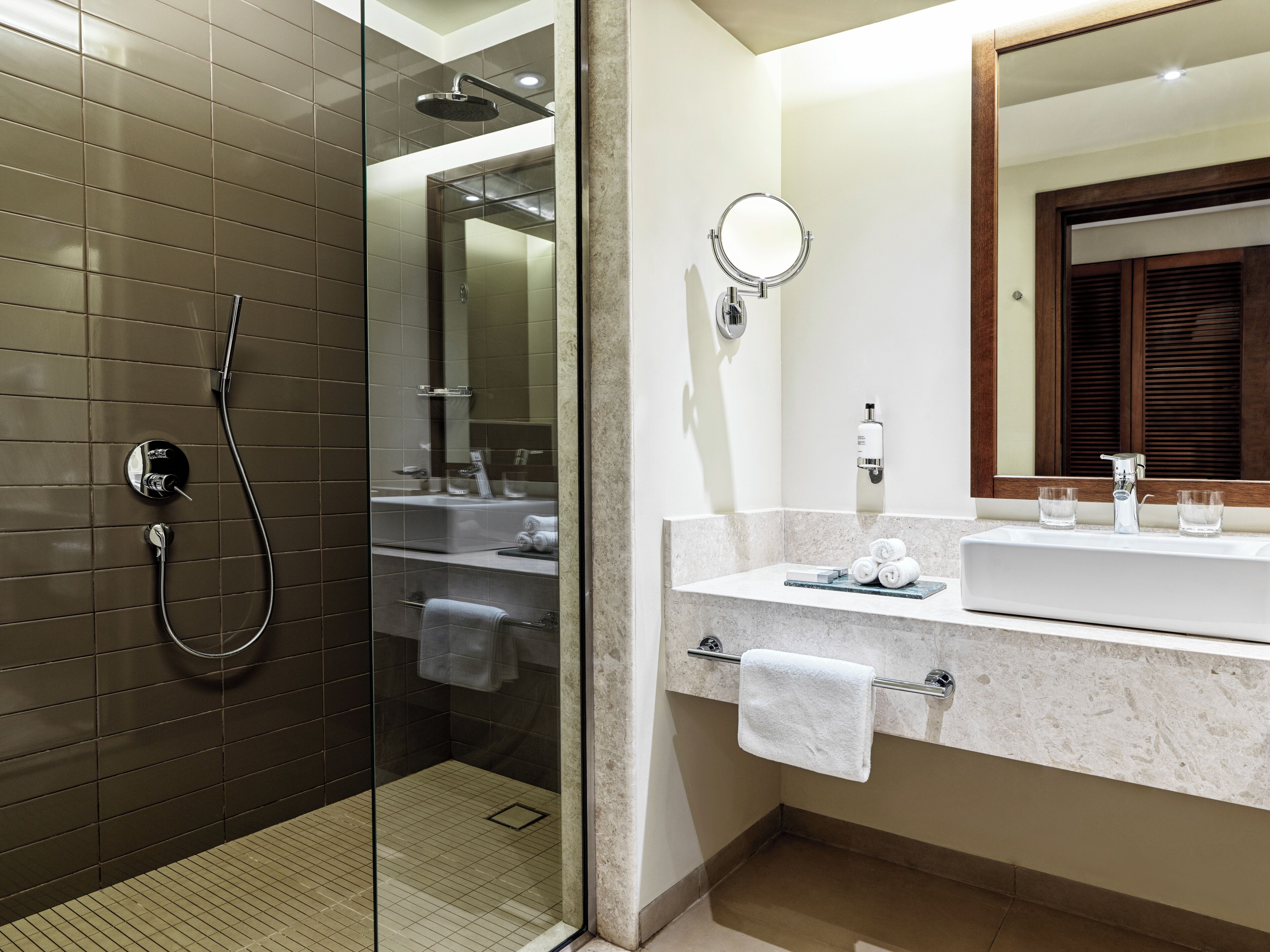 A modern bathroom with a glass-enclosed shower, a vanity with a marble countertop, and a large mirror above the sink.