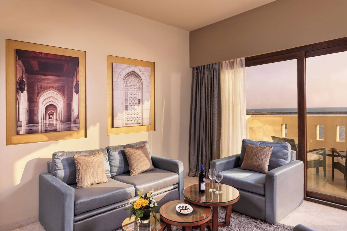 A modern living room with two sofas, a glass coffee table, and a view of the sea through large windows.
