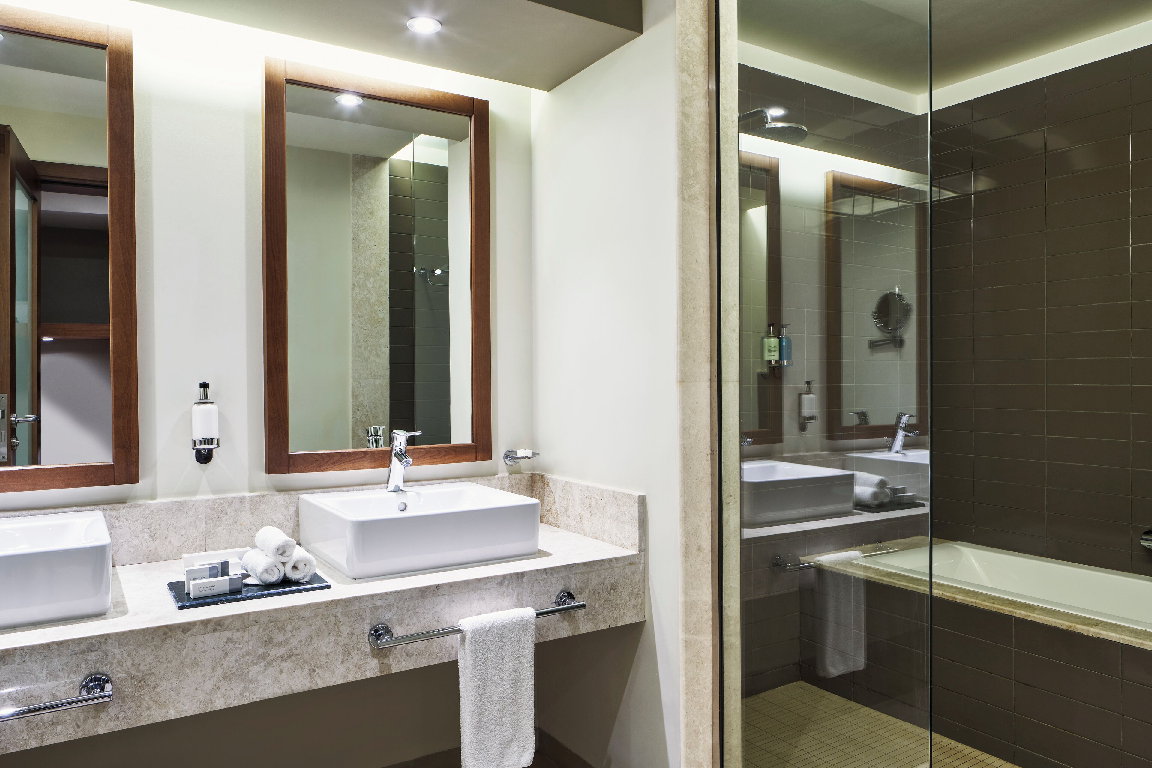 Une salle de bain moderne avec deux vasques, une douche à l’italienne et un comptoir en marbre.