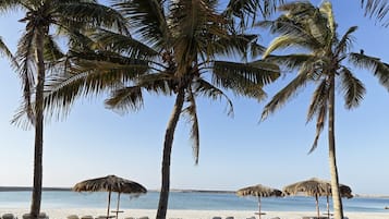 En privat strand, hvidt sand, liggestole, parasoller