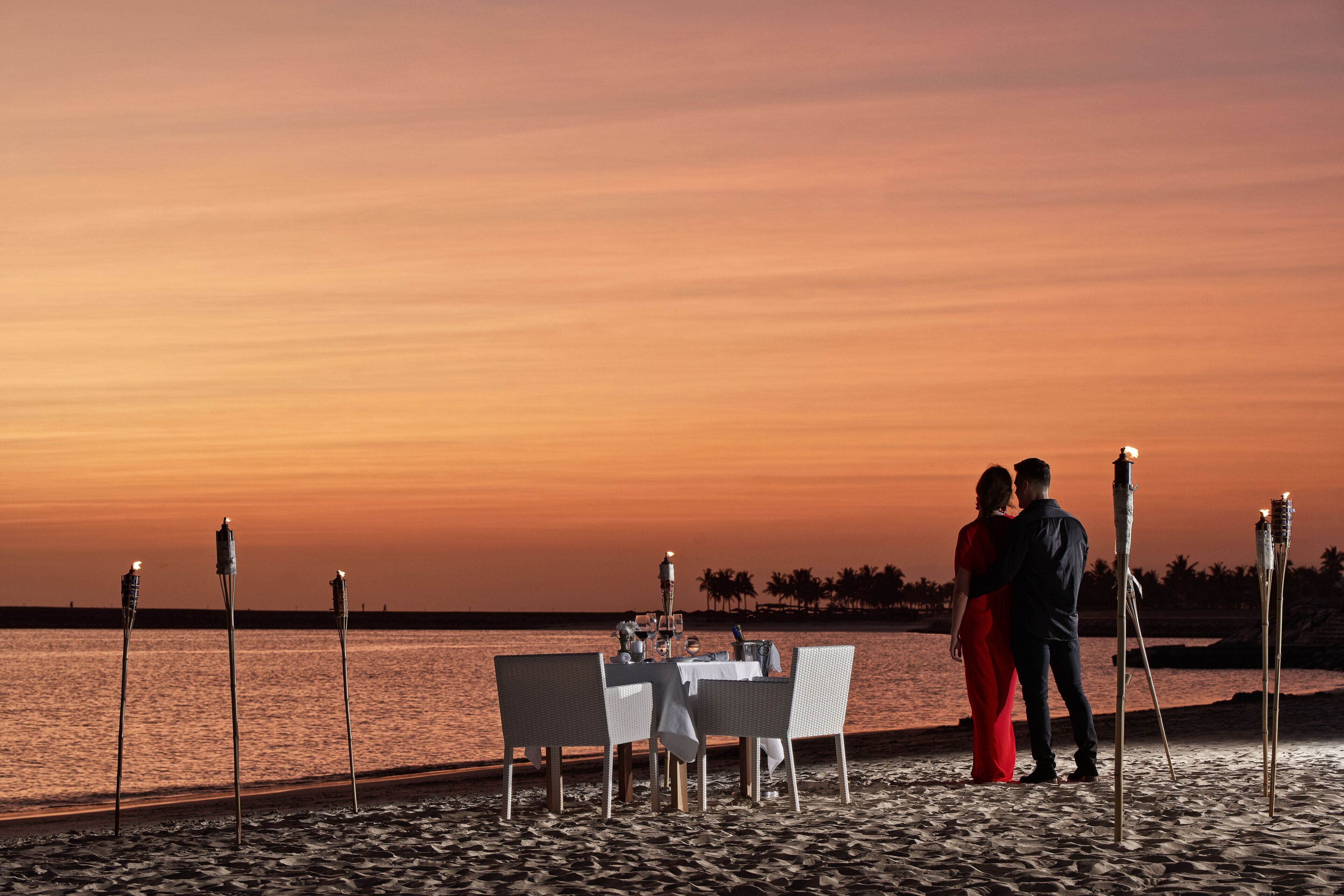Un montaje para comer frente al mar, con una mesa y sillas, con vistas a la puesta de sol.