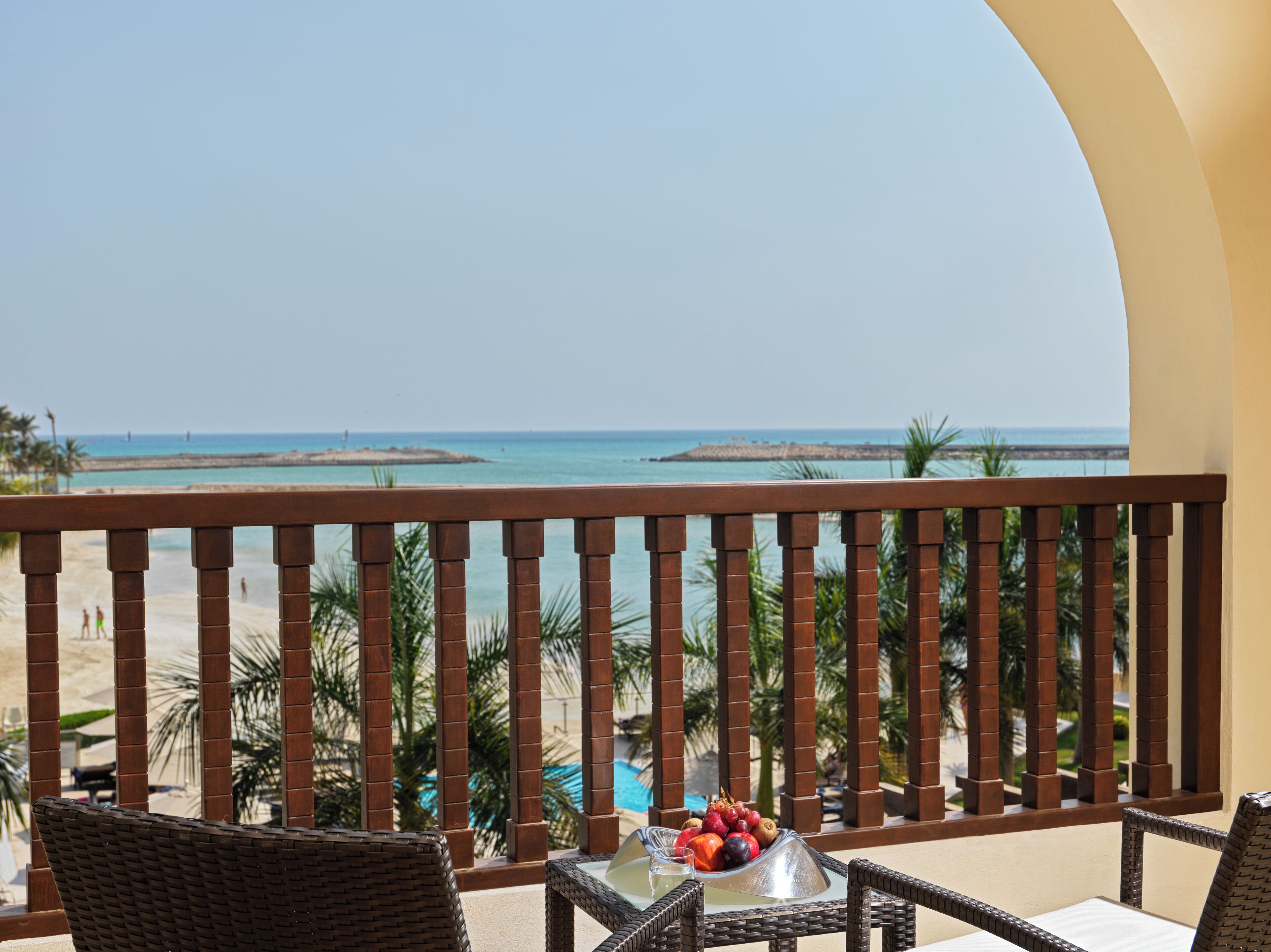 Ein Balkon mit Korbm öbeln, einer Obstschale und Blick auf Strand und Meer.