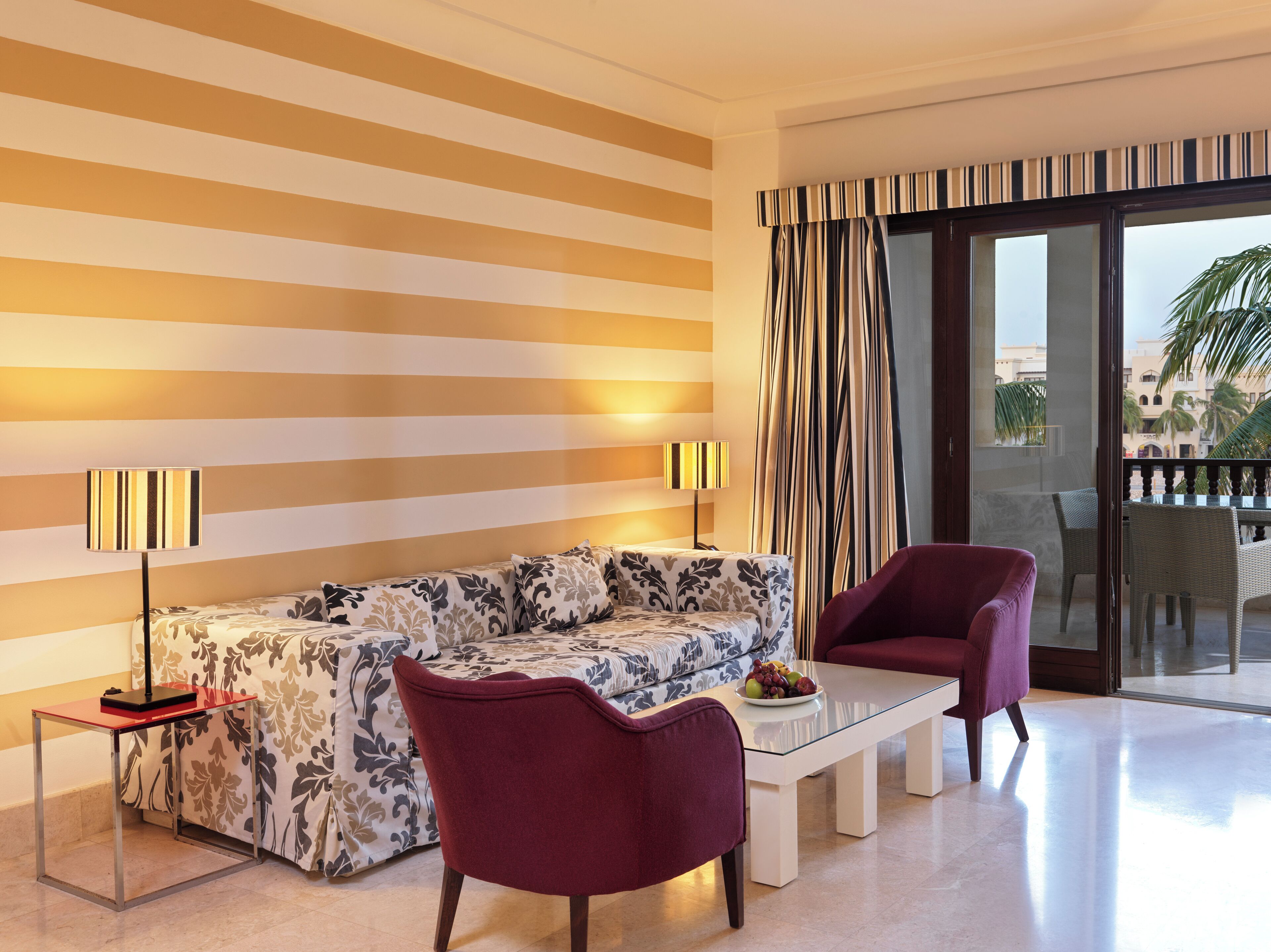 A modern living room with a striped wall, a sofa, two armchairs, a coffee table, and a balcony with curtains.