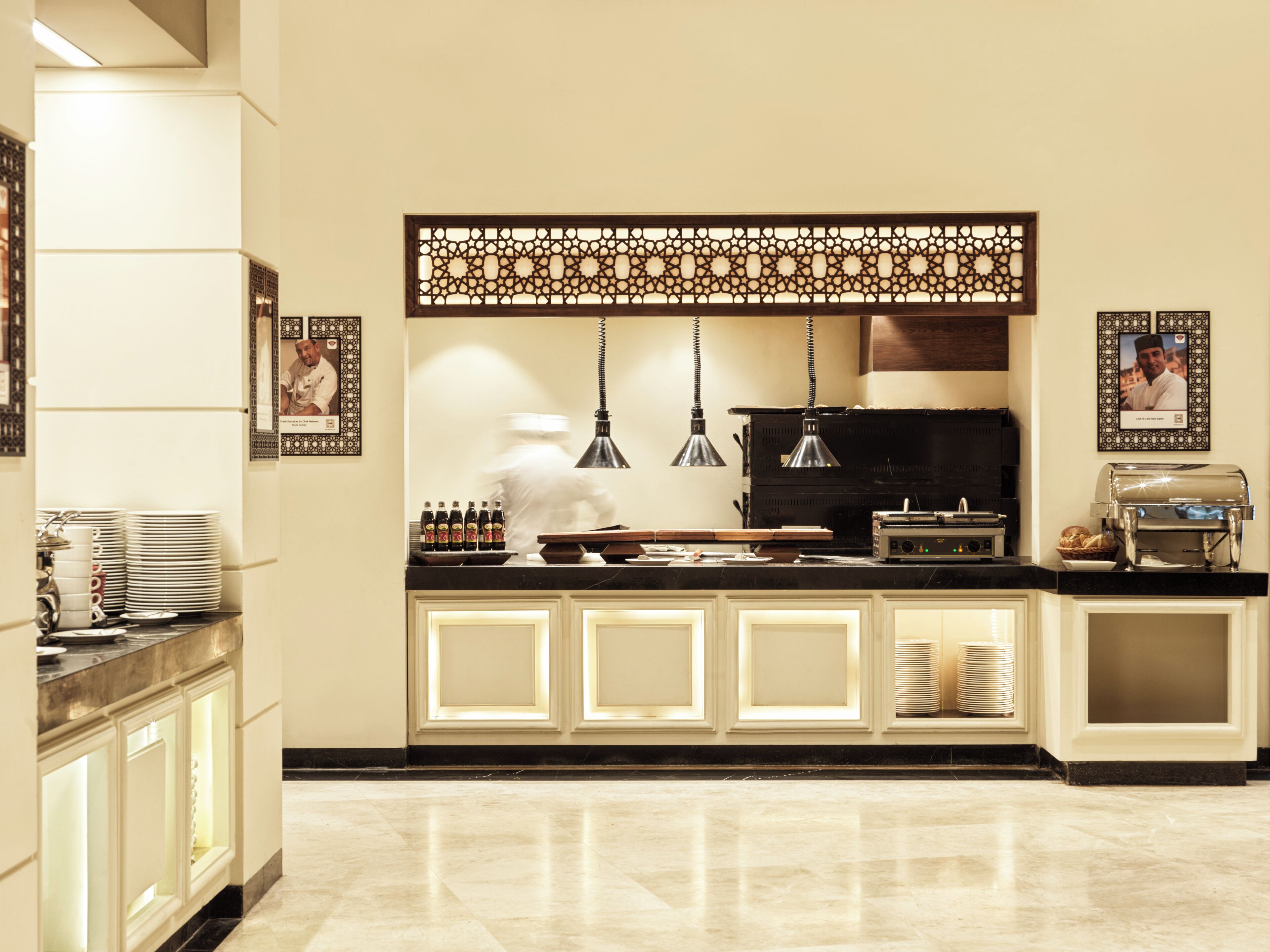 Een moderne keuken met een marmeren aanrecht, een koffieapparaat en een decoratief scherm.