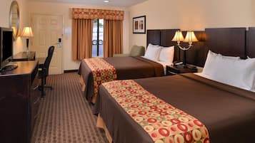A hotel room with two beds, a desk, a chair, a TV, and a window with curtains.