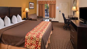 A hotel room with a large bed, a desk with a chair, a television, and a window with curtains.