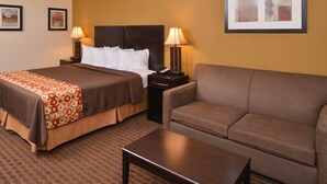 A hotel room with a bed, two bedside tables with lamps, a sofa, and a small table. - Americas Best Value Inn Tupelo Barnes Crossing (Tupelo)