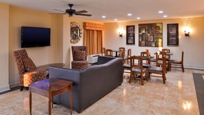 A living room with a sofa, chairs, a coffee table, a flat-screen TV, a ceiling fan, and artwork on the walls. - Americas Best Value Inn Tupelo Barnes Crossing (Tupelo)
