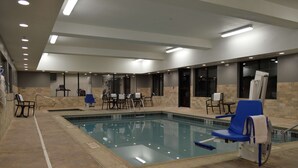 A pool area with a rectangular pool, blue lounge chairs, and a seating area with tables and chairs. - Best Western Plus Stevens County Inn (Hugoton)