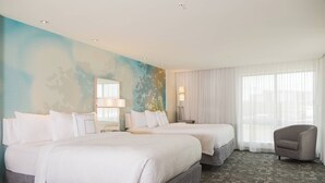 A hotel room with two beds, a chair, a large window with sheer curtains, and a wall with a blue abstract design.