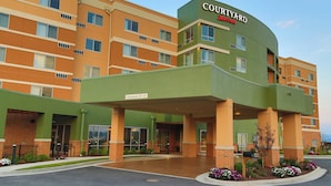 A Courtyard by Marriott hotel with a green and orange facade, a covered entrance, and a sign indicating a clearance of 12 feet.
