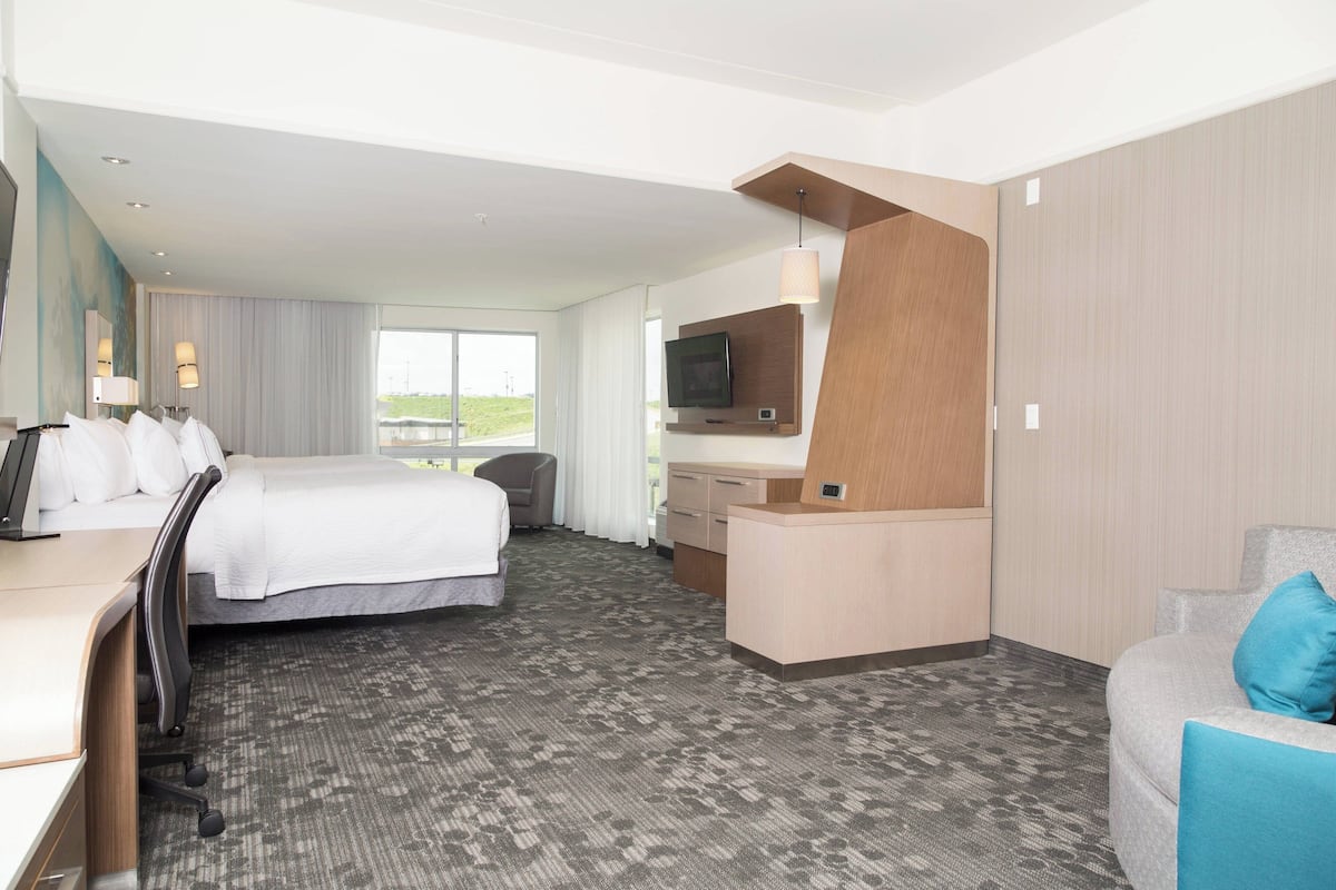A hotel room with a bed, desk, chair, and a TV.