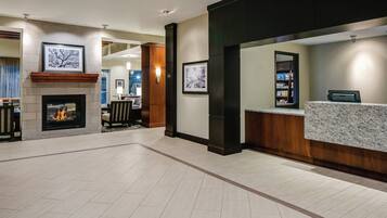 A hotel lobby with a fireplace, framed artwork, a reception desk, and a seating area.