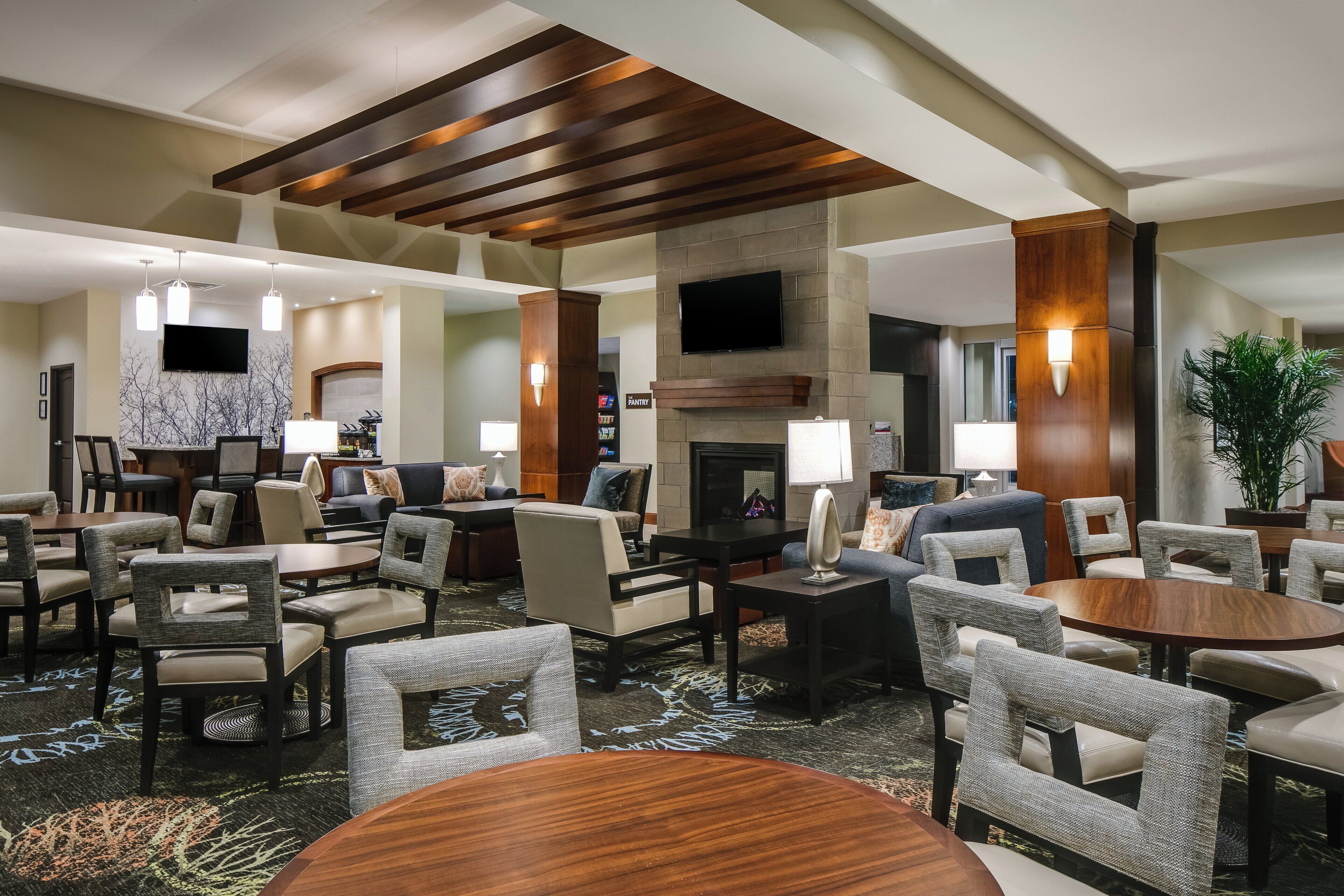 A hotel lobby with multiple seating areas, a fireplace, and a television mounted on the wall.