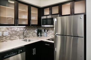 Una cocina moderna con electrodomésticos de acero inoxidable, muebles oscuros y salpicadero de azulejos.