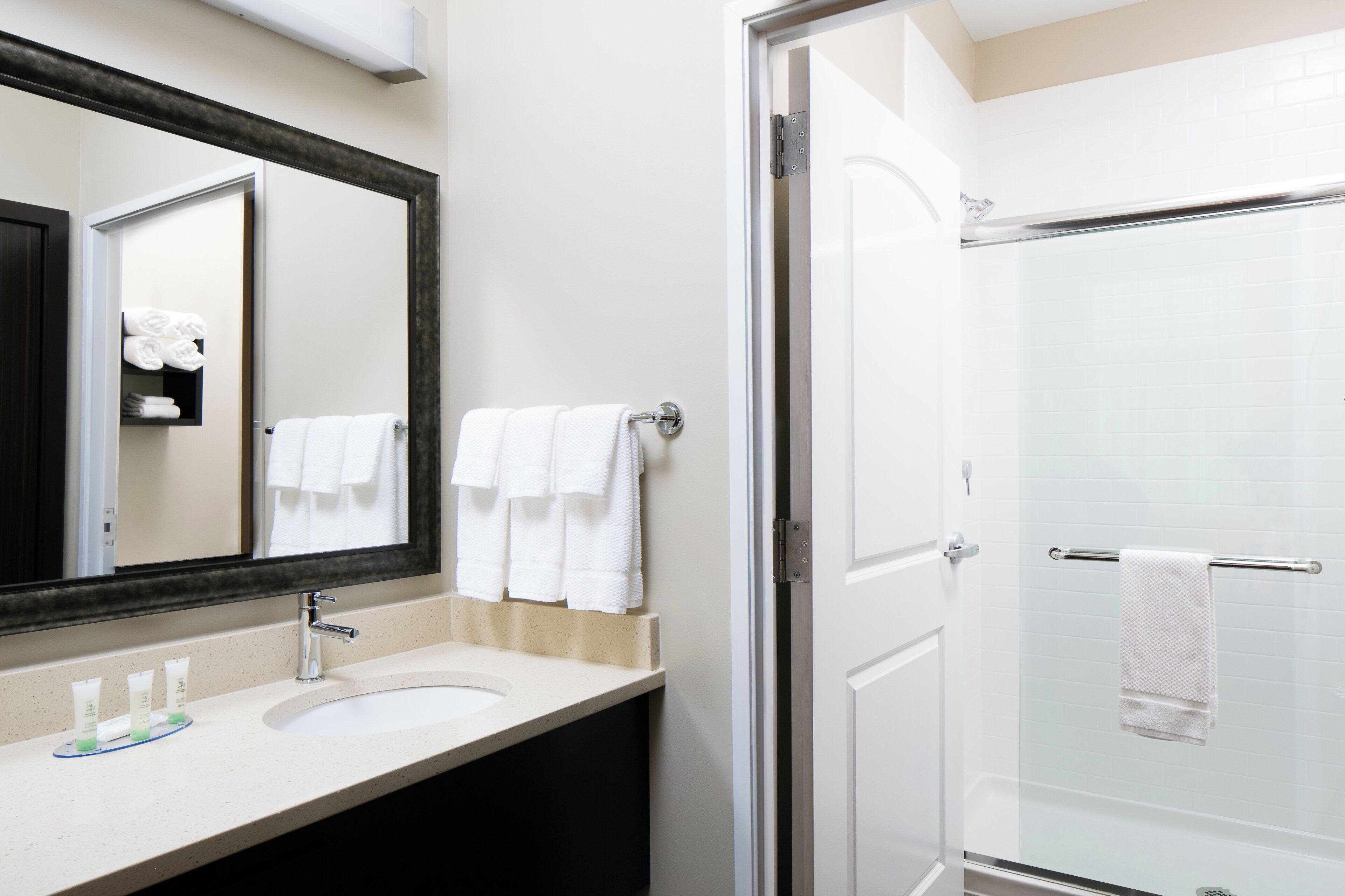 A bathroom with a sink, mirror, and shower.