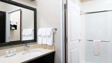 A bathroom with a sink, mirror, and shower.